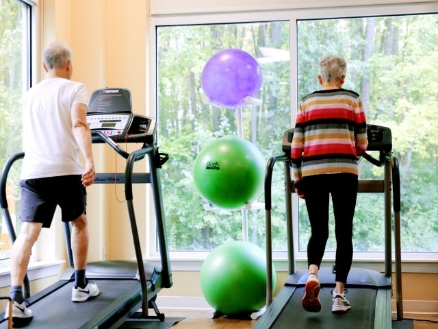 older man and woman walking on treadmill 