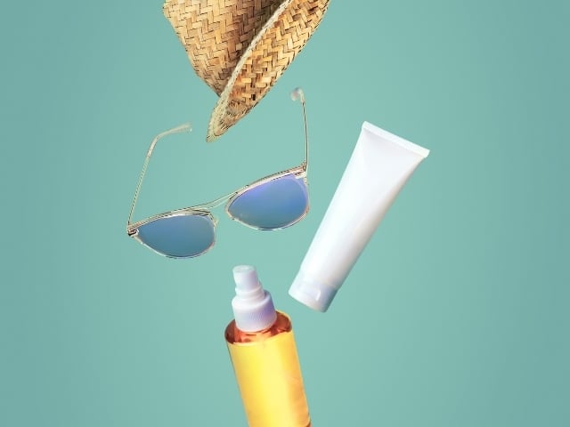 Green background, sunglasses, SPF, and suntan lotion 