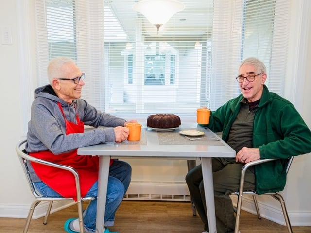 Bill and Tom sitting at a table drinking coffee 