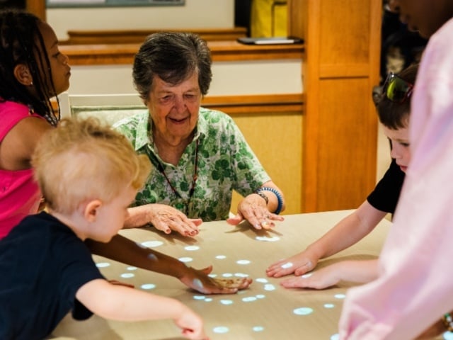 older woman playing game with three children 