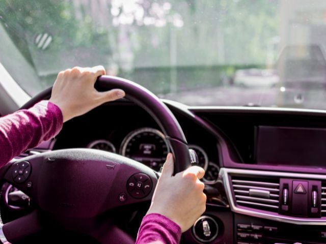 Person with hands on wheel of car
