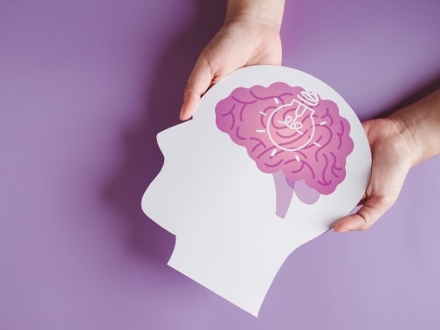 person holding cut out of a head with brain and purple background