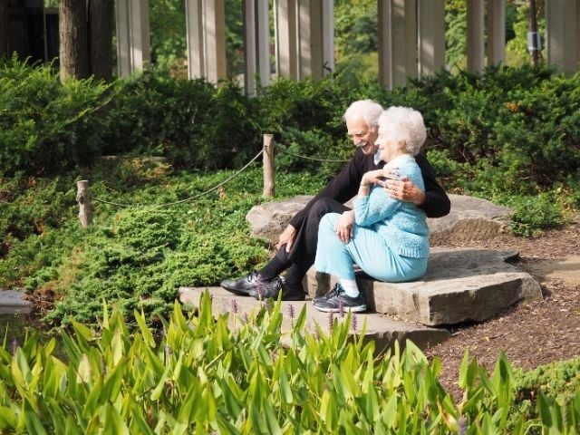 older couple sitting in embrace in garden