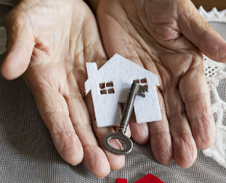 elder hands holding a house key