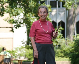 older adult woman on a campus holding folders