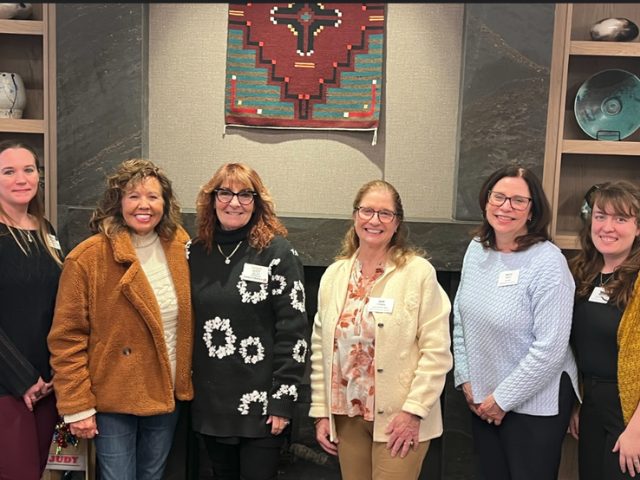 six women standing in front of a fireplace