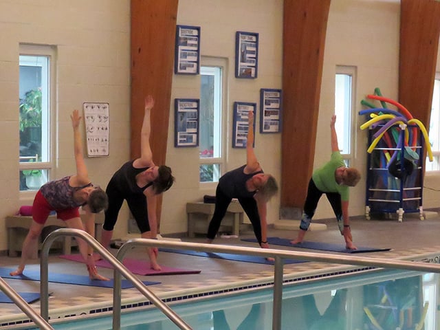 women practice yoga at pool