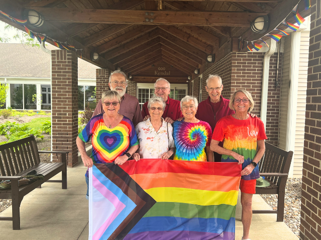 gorup of people standing together holding pride flag