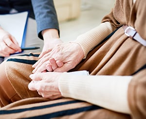 A woman supporting an older adult who is coping with grief