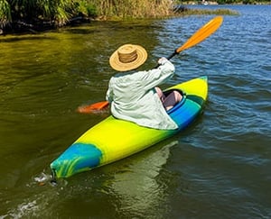 Senior woman kayaking down a river.