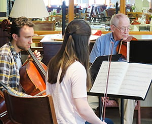 Older man playing music with young adults